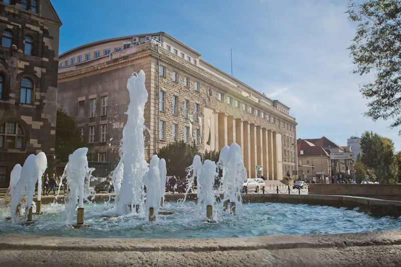 Fontanna Alei Niepodległości, na jej tle widnieje Budynek A Uniwersytetu Ekonomicznego w Poznaniu z lewej perspektywy.