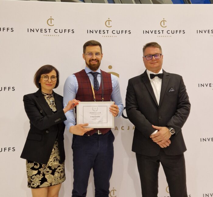 Dr Wojciech Świder, ubrany w kamizelkę i krawat, otrzymuje Srebrny Laur w kategorii „Influencer rynku” na tle ścianki z logotypem „Invest Cuffs”. Po jego lewej stronie stoi kobieta w okularach, czarnej marynarce i złotej sukience, a po prawej stronie mężczyzna w garniturze i muszce.